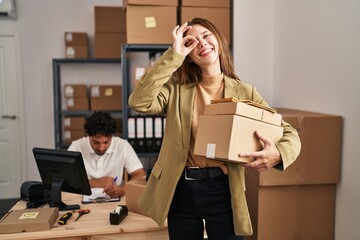 Poster - Young two people working at small business ecommerce smiling happy doing ok sign with hand on eye looking through fingers