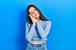 © Krakenimages.com - Young brunette teenager wearing casual sweater sleeping tired dreaming and posing with hands together while smiling with closed eyes.