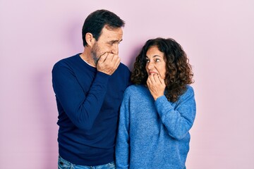 Poster - Middle age couple of hispanic woman and man hugging and standing together looking stressed and nervous with hands on mouth biting nails. anxiety problem.