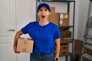 Poster - Middle age brunette woman working wearing delivery uniform and cap angry and mad screaming frustrated and furious, shouting with anger. rage and aggressive concept.