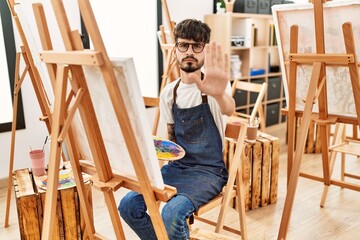 Poster - Hispanic man with beard at art studio with open hand doing stop sign with serious and confident expression, defense gesture