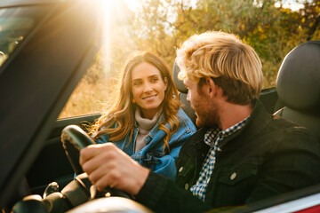 Wall Mural - White couple smiling together while driving in car during trip