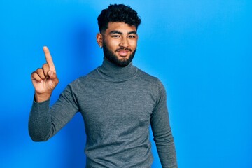 Poster - Arab man with beard wearing turtleneck sweater pointing finger up with successful idea. exited and happy. number one.