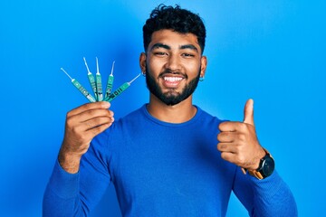 Wall Mural - Arab man with beard holding picklock to unlock security door smiling happy and positive, thumb up doing excellent and approval sign