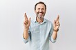 Middle age hispanic man with beard standing over isolated background gesturing finger crossed smiling with hope and eyes closed. luck and superstitious concept.