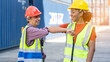 © Yellow Boat - Warehouse business. A Chinese man and a african american woman in safety suit elbow bump and conclude a job for transport and logistics after  Successfully completed business Contract
