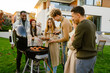 © Drobot Dean - White man grilling meat during barbeque with his friends on backyard