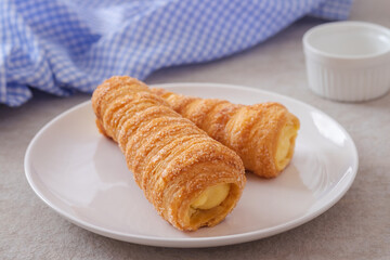 Puff pastry cream horn with vanilla cream on plate