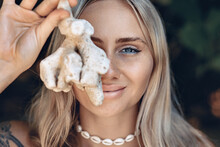Portrait Of A Beautiful Blond Girl With A Bright Deep Eyes Covering With A Blue Liner Holding A Small Coral In Her Hand. Close Up.