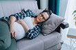 © Olga - Depression in pregnancy. Young sad lonely pregnant woman lying on sofa at home, having depressed mood. Upset tired expectant mother feel fatigued during third trimester. Maternal mental health