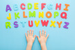 Toddler boy hands with colorful letters on light blue table background. Pastel color. Time to learning English alphabet. Point of view shot. Closeup. Top down view.
