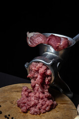 Canvas Print - Meat in a meat grinder on a black background. Pork meat is twisted in an old meat grinder. meat cooking.