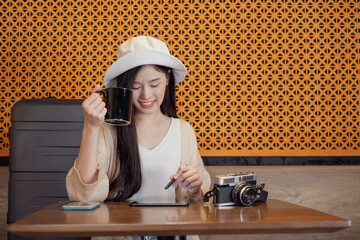 Young tourist woman using tablet in a cafe. Young traveller woman sitting in a cafe and using smartphone. Happy young female sitting in cafe holding digital tablet in hand.