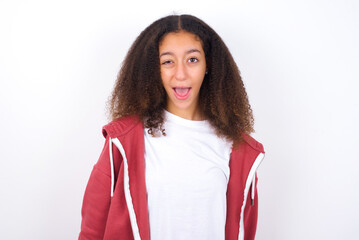 teenager girl wearing pink jacket standing against wite background winking looking at the camera wit