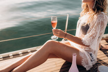 Blonde Girl In A Bikini With A Glass Of Champagne Relaxes On A Yacht In The Middle Of The Ocean