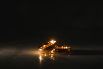 Wall Mural - Elegant wedding rings for the bride and groom on a black background with highlights, macro, selective focus