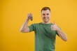 © Serhii - man with car keys on a yellow background, buying a new car