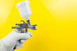 Manual and paint spray gun at work on a yellow background