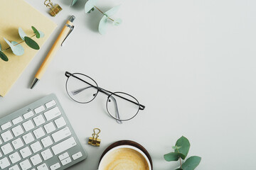 Canvas Print - Flat lay office desk table with glasses, computer keyboard, paper notebook, pen, eucalyptus branches. Elegant feminine workspace, view from above.