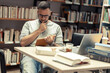 © BalanceFormCreative - Male student studying in campus library .He reads a book.