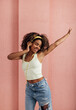 © Artem Varnitsin - Young female having fun at pink wall. Woman wearing yellow headphones and dancing.
