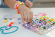 © New Africa - Little girl making beaded jewelry at table, closeup