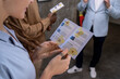 © pressmaster - Close-up of young woman examining the guide about the artwork with other people during excursion in art gallery