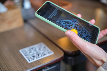 Closeup of guest hand ordering meal in restaurant while scanning qr code with mobile phone for online menu