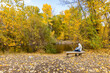 © Tetra Images - USA, Idaho, Hailey, Rear view of senior woman relaxing on bench by river in Autumn