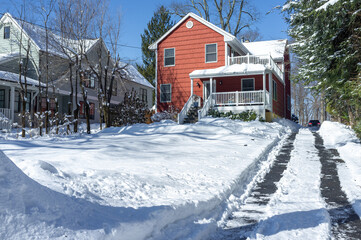 Wall Mural - red suburban house and driveway with car tracks cleaned the day after the snow storm