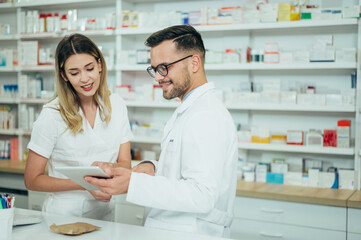 Happy young male and female colleagues pharmacist working in a pharmacy