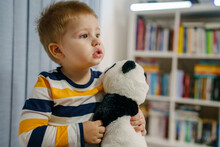 Waist Up Portrait Of One Small Caucasian Boy Two Years Old Holding Panda Toy While Standing Alone At Home Looking To The Side Copy Space Childhood And Growing Up Concept