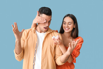 Poster - Young woman proposing to her shocked boyfriend on color background