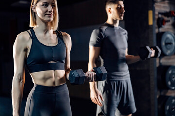 Sporty couple exercising with dumbbells in a gym.