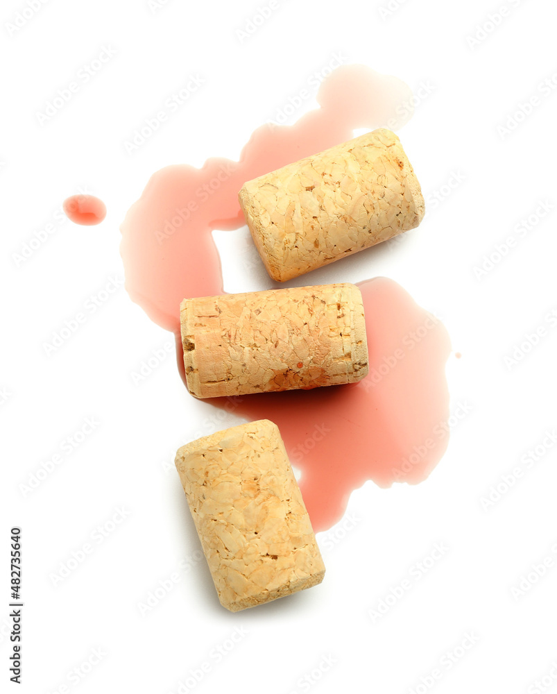 Spilled wine and corks on white background
