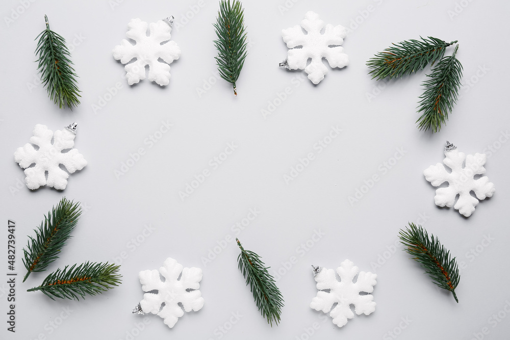 Frame made of snowflakes and fir branches on light background
