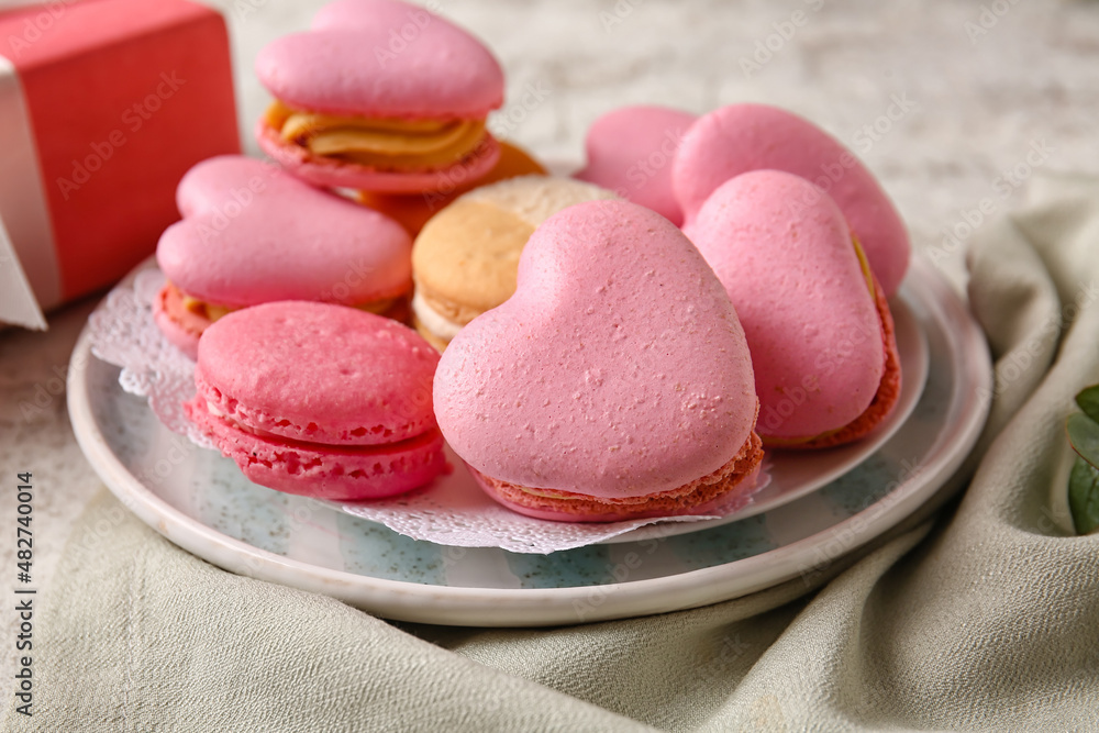 Plate with tasty heart-shaped macaroons on light background, closeup