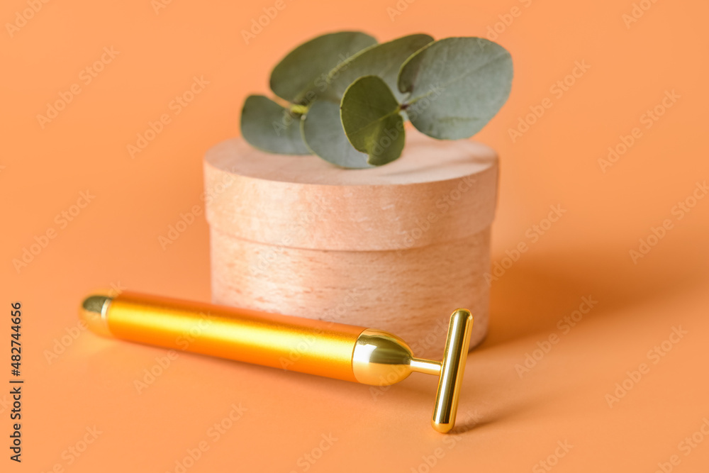 Face massage roller with wooden box on color background