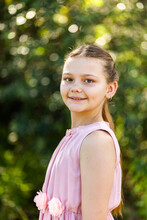 Portrait Of Young Ten Year Old Girl With Natural Green Bokeh Background