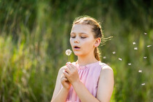 Happy Young Tween Girl Outside Blowing Dandelion Flower Seeds