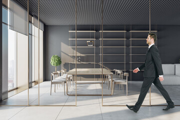 Poster - Businessman walking in modern conference room interior with window and city view, glass partition and daylight. Workplace concept.