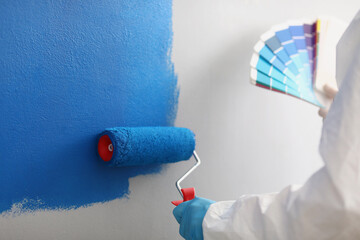 Wall Mural - Painter with brush tool covered in blue colour painting wall, worker on site