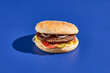 Beef burger blue background with hard shadow. American junk food minimal style. Hamburger trendy style.  Simple burger colour background.