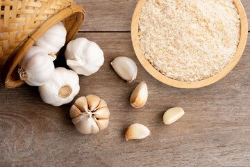 Poster - Garlic powder in wooden bowl and bulb of garlic isolated on wooden table background. Top view. Flat lay.