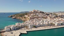 Aerial View Of Ibiza City, The Old Town And The City Walls Of Eivissa With An Ocean Foreground, Filmed By Drone, On A Sunny And Clear Day.