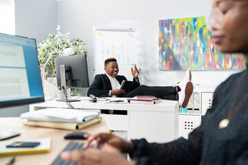 Wall Mural - The handsome boss of company sits comfortably in chair with feet on desk leans on it quickly comes up with a brilliant idea rises up holding the tablet in hand gestures