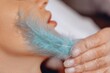 © Semachkovsky  - The result of high-quality service in a beauty salon. Smooth and well-looking skin after the lifting machine procedure. The master leads a soft blue feather over the girl's skin.
