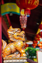 Blurred Background. Chinese Lion Statue Guarding The Door, Made Of Wood Carving In A Chinese Temple