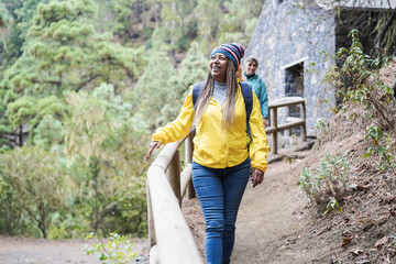 Wall Mural - Multiracial group of women having fun exploring nature in mountain forest - Focus on african female face