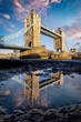 Low angle view of the iconic Tower Bridge in London. England, during sunrise with reflections in a water puddle